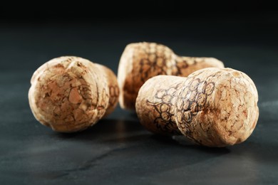 Corks of wine bottles with grape images on black table, closeup