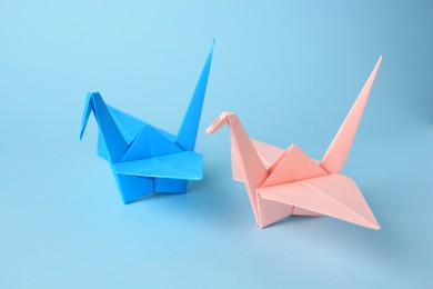 Photo of Origami art. Colorful handmade paper cranes on light blue background
