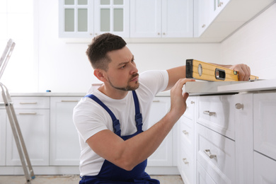 Worker measuring countertop with spirit level in kitchen