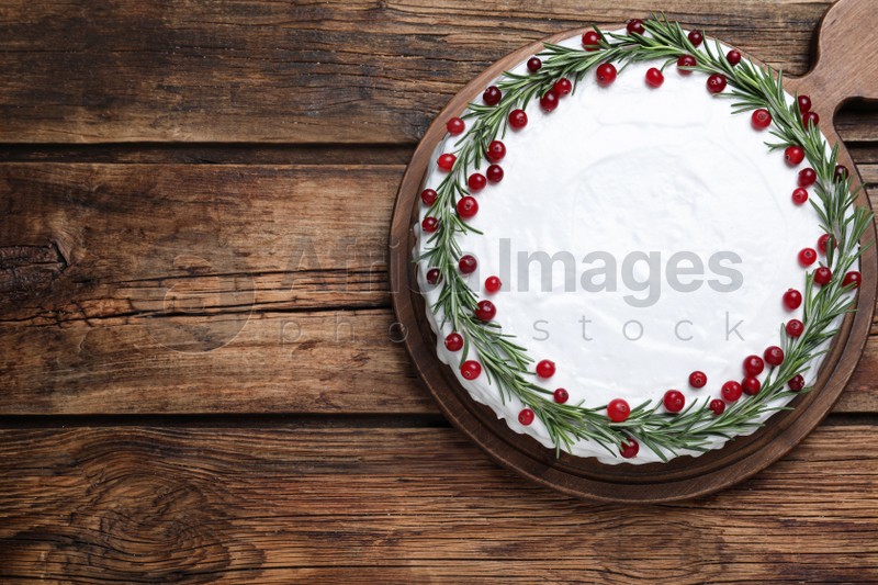 Photo of Traditional Christmas cake decorated with rosemary and cranberries on wooden table, top view. Space for text