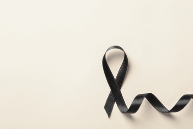 Black ribbon on light background, top view. Cancer awareness