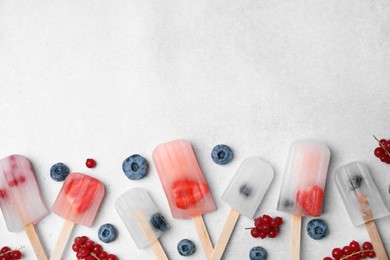 Photo of Flat lay composition with tasty berry ice pops on light table. Space for text