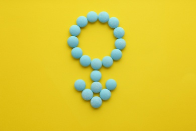 Male sign made of blue pills on yellow background, flat lay. Potency problems