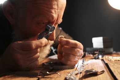 Male jeweler evaluating diamond ring in workshop