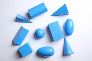 Photo of Set of blue wooden geometrical objects on white background, top view. Montessori toy