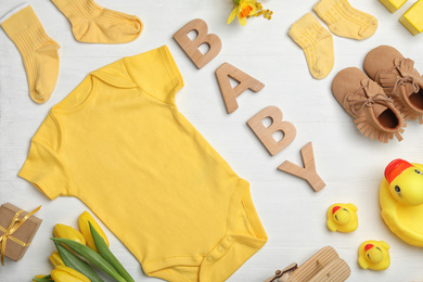 Flat lay composition with child's clothes and word Baby on white wooden table