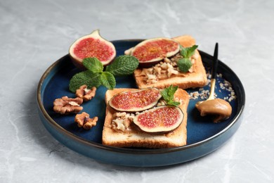 Tasty toasts served with fig, peanut butter and walnuts on light grey marble table