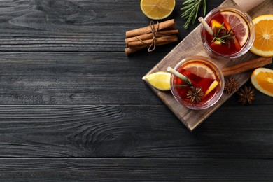 Aromatic punch drink and ingredients on black wooden table, flat lay. Space for text