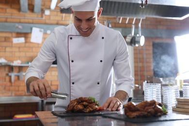 Professional chef with delicious fried chicken wings in restaurant kitchen