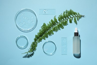 Flat lay composition with cosmetic product, fern and laboratory glassware on light blue background
