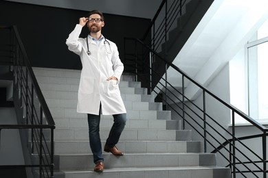 Photo of Doctor with stethoscope on stairs in hospital. Space for text