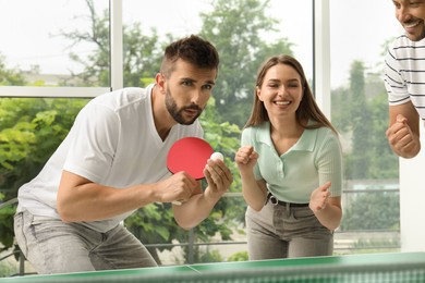 Happy friends playing ping pong together indoors