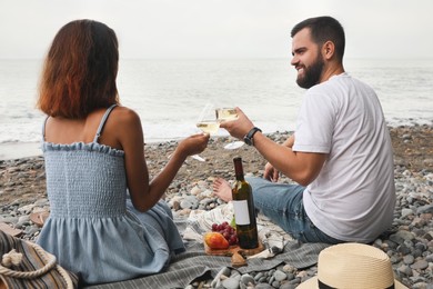 Happy young couple having picnic on beach near sea