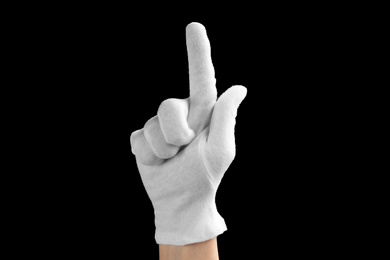 Person in white glove showing clean finger on black background, closeup