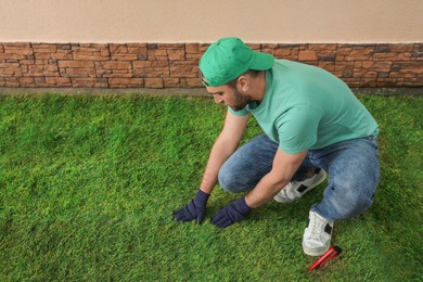 Photo of Worker laying grass sod at backyard, space for text