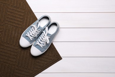 New clean door mat with shoes on white wooden floor, flat lay. Space for text