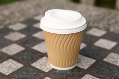 Paper cup on stone table, closeup. Coffee to go
