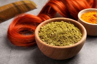 Photo of Red strand, henna and turmeric powder on grey table, closeup. Natural hair coloring
