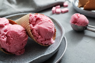 Delicious pink ice cream in wafer cones served on grey table, closeup