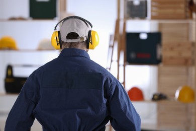 Worker wearing safety headphones indoors, back view. Hearing protection device