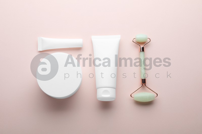 Natural face roller and cosmetic products on pink background, flat lay