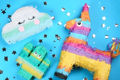 Photo of Different bright pinatas on light blue background, flat lay