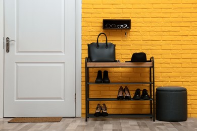 Shelving unit with shoes near yellow brick wall in hallway