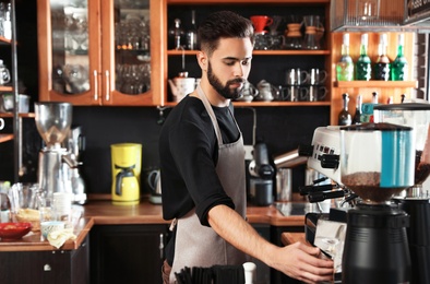 Photo of Portrait of barista using coffee grinding machine in cafe