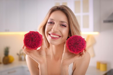 Photo of Young woman with fresh pitahaya in kitchen. Exotic fruits