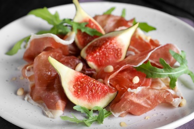 Photo of Delicious figs and proscuitto on plate, closeup