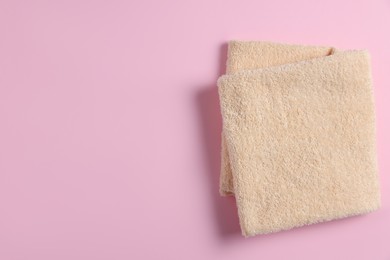 Soft folded towel on pink background, top view. Space for text