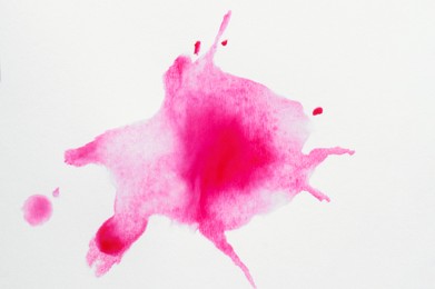 Photo of Pink ink blots on white canvas, top view