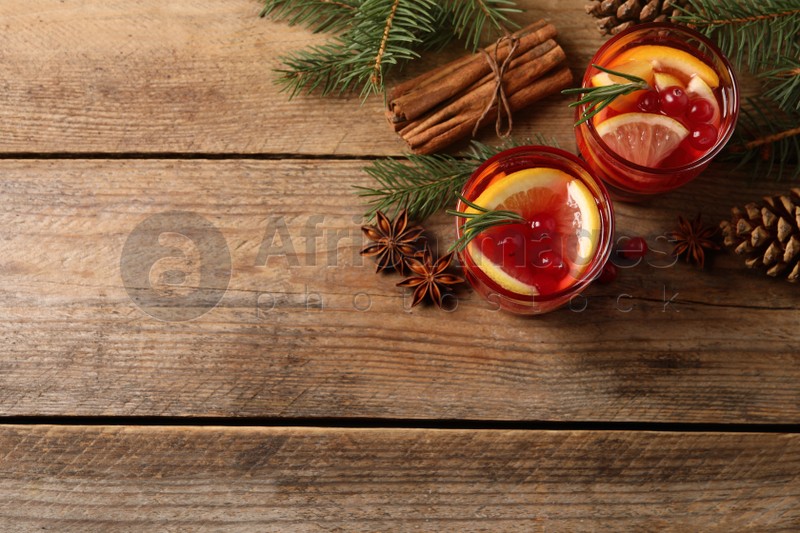 Delicious punch drink with cranberries, orange and spices on wooden table, flat lay. Space for text