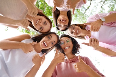 Happy women showing thumbs up outdoors, bottom view. Girl power concept