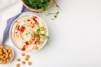 Delicious hummus with chickpeas and paprika served on white table, flat lay. Space for text