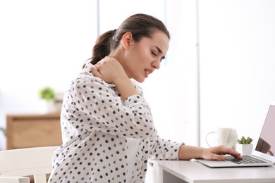 Photo of Woman suffering from neck pain in office. Bad posture problem