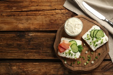 Photo of Delicious sandwiches with cream cheese and other ingredients on wooden table, flat lay. Space for text