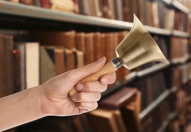 Woman with school bell in library, closeup