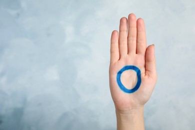 Woman showing blue circle drawn on palm against color background, closeup. World Diabetes Day