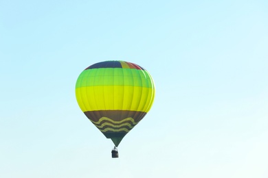 Colorful hot air balloon flying in blue sky. Space for text