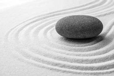 Grey stone on sand with pattern. Zen, meditation, harmony