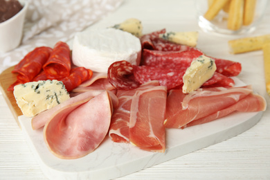 Photo of Tasty ham with other delicacies served on white wooden table, closeup