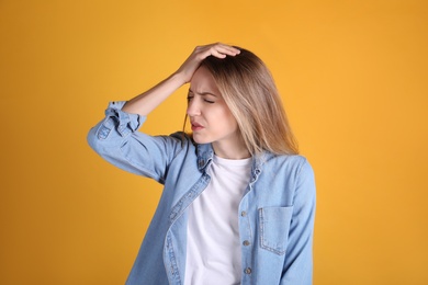 Portrait of stressed young woman on yellow background