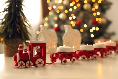Red toy train as Christmas candle holder on white table in room
