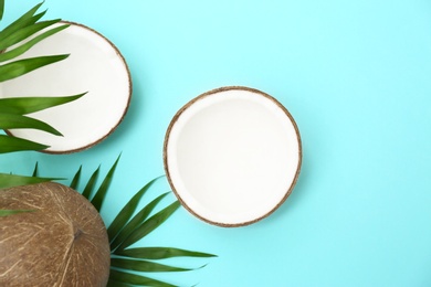 Fresh coconuts and palm leaves on light blue background, flat lay