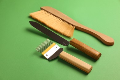 Three different beekeeping tools on green background