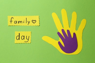 Paper palms and cards with text Family Day on light green background, flat lay