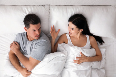 Couple quarreling in bed at home, top view. Relationship problems