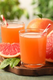 Glasses of delicious grapefruit juice on wooden table against blurred background