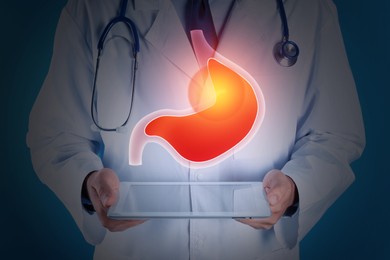 Image of Treatment of heartburn and other gastrointestinal diseases. Doctor using tablet on dark background, closeup. Stomach illustration over device